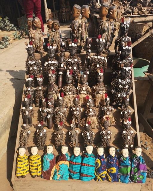 Rows of carved wooden figures, shell-decorated objects and small dolls wrapped in colourful cloth.