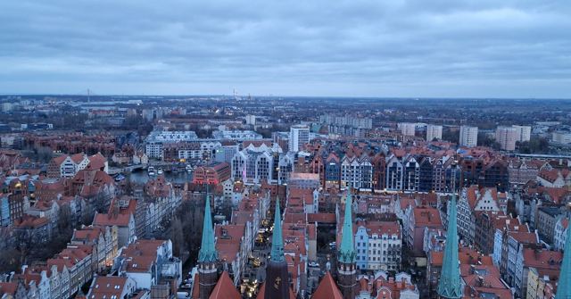 An elevated view over Gdańsk's red rooftops and church spires stretching to the horizon.