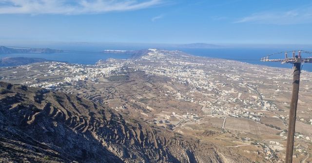 A high view over Santorini's dry hills and white villages stretching to the sea.
