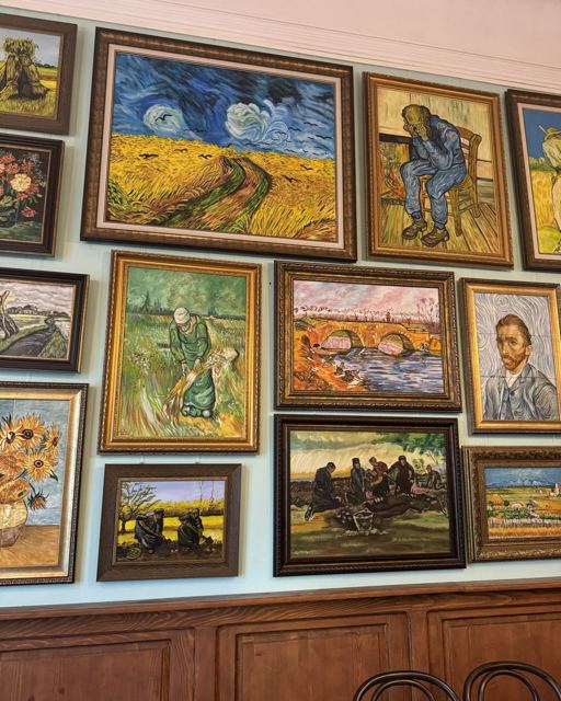 Wall covered with framed paintings in the style of Van Gogh, including a self-portrait.