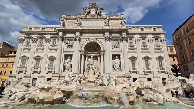 The baroque Trevi Fountain with marble statues and turquoise pool in front of a palace facade.