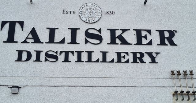 The words Talisker Distillery, established 1830, painted in black on a white wall.