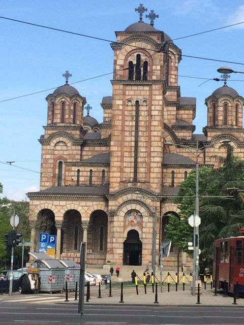 The red and cream Church of St Mark in Belgrade under a blue sky