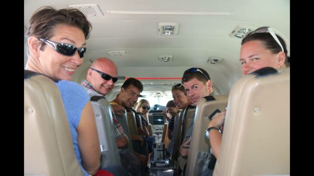 A group of travellers smiling in the seats of a minibus on the way to the Nazca Lines.