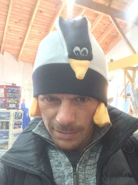 A man wearing a novelty penguin hat in a souvenir shop.