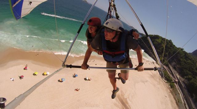 A tandem hang glider about to touch down on a sandy beach, seen from the wing.