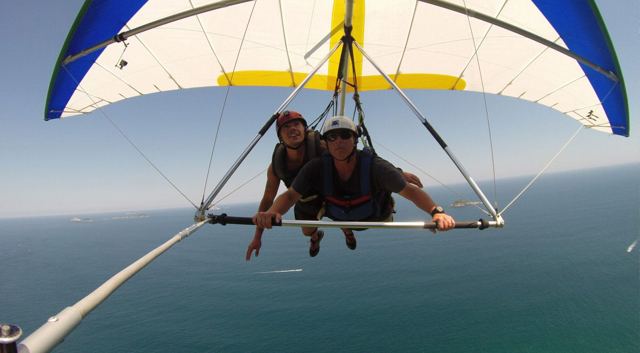 Two people tandem hang gliding over the ocean off Rio de Janeiro.