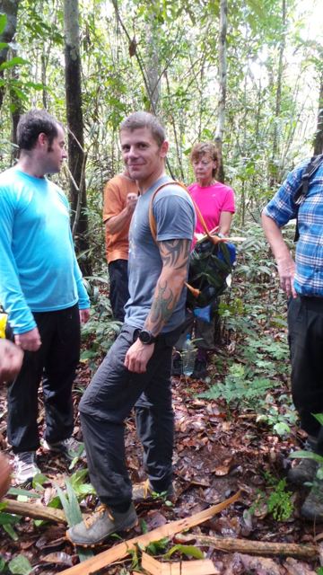 A group of hikers in the rainforest, with a man looking back over his shoulder.