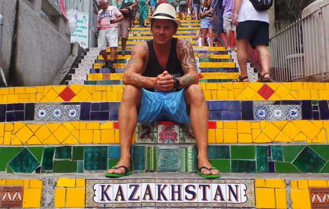 A man sitting on colourful tiled steps above a tile reading Kazakhstan.