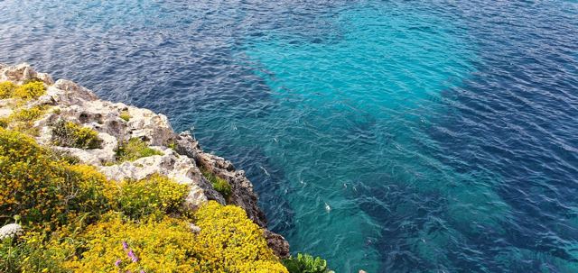 Turquoise water below the rocky coast of Menorca.