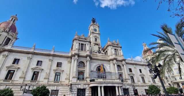 Valencia's ornate white City Hall with a clock tower under a bright blue sky, palm trees to the side.