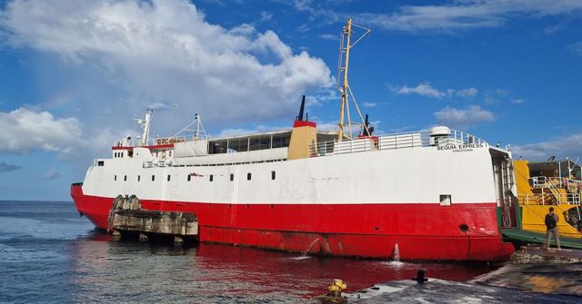 A red and white ferry moored at a dock in Kingstown harbour under blue skies.