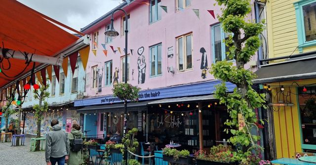 A street of brightly painted buildings with bunting and café tables in Stavanger.