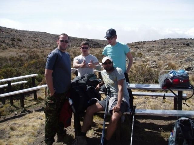 Hikers resting by picnic benches on rocky moorland high on Mount Kilimanjaro.