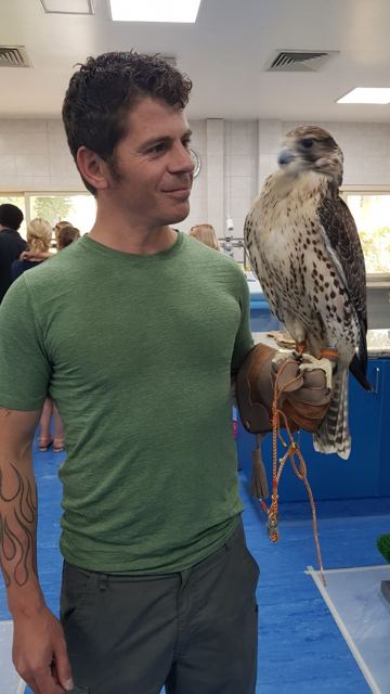A man holding a falcon on a gloved hand inside a hospital room.