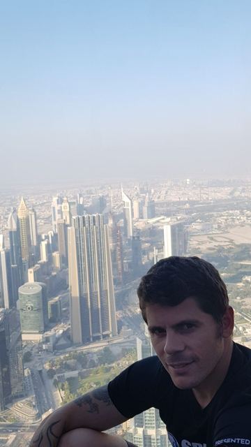 A man at a window high above the skyscrapers of downtown Dubai.