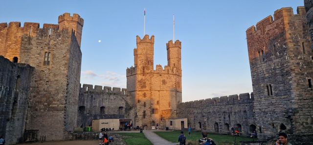 The walls and towers of Caernarfon Castle at dawn.