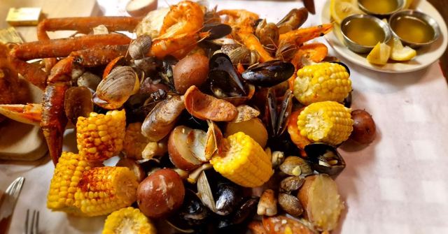 A seafood boil of crab legs, mussels, clams, corn and sausage with dipping butter on the side.