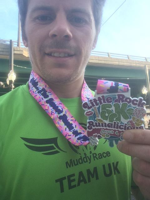 A man in a green Team UK top taking a selfie with a huge colourful race medal.