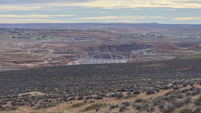 Wide desert landscape of scrub and red rock plateaus under a pale morning sky near Page, Arizona.