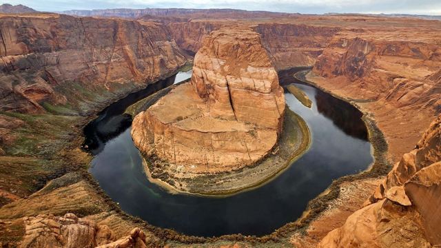 Horseshoe Bend, where the green Colorado River loops around a huge sandstone outcrop in a deep red canyon.