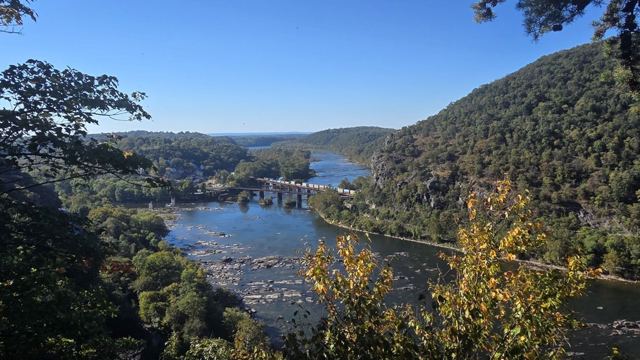 Elevated view of a river valley with bridges and a small town between forested hills.