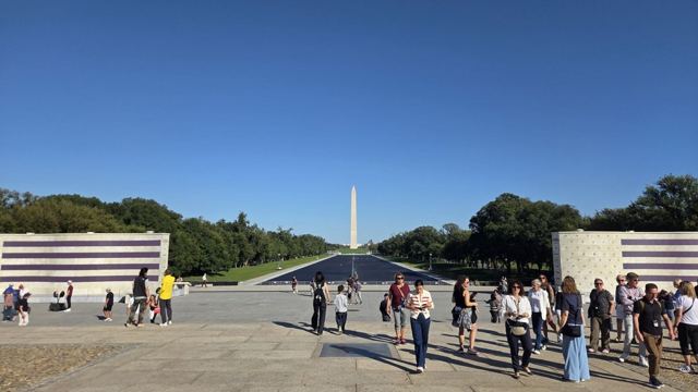 View across a plaza along the National Mall to the Washington Monument, visitors walking in the foreground.