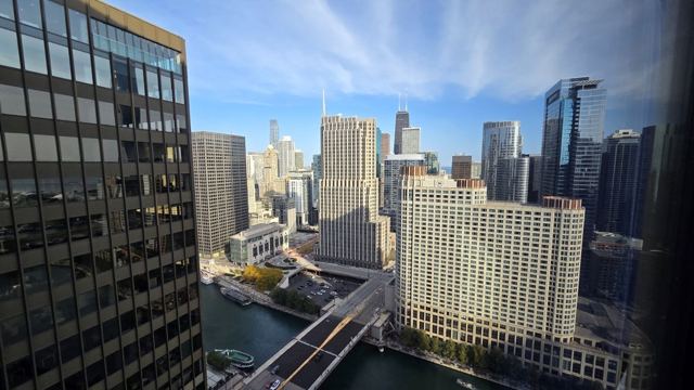 View from a high window over the Chicago River lined with skyscrapers and bridges.