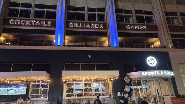 Evening view of a building front with signs for cocktails, billiards and games.