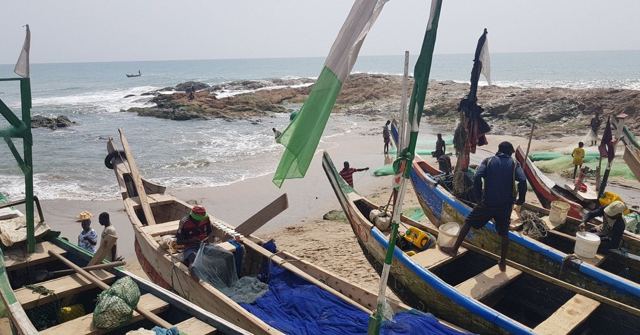 Colourful wooden fishing canoes with flags on a beach beside the sea.