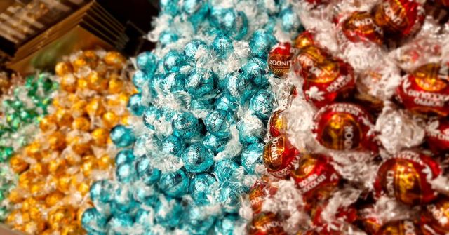 Piles of chocolate truffles in gold, teal and red foil wrappers.